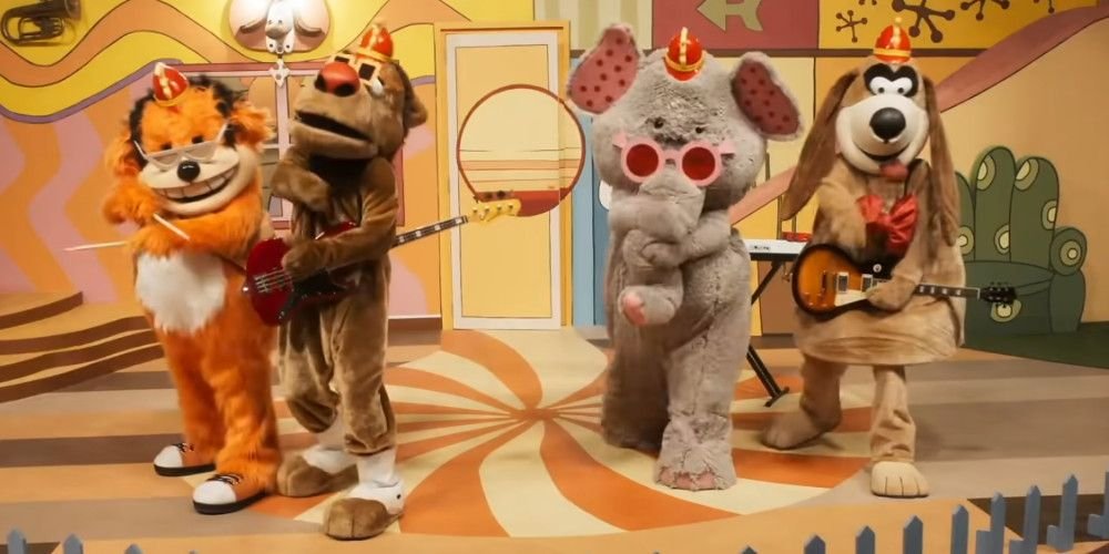 Four mascot characters from The Banana Splits stand on a stage with instruments