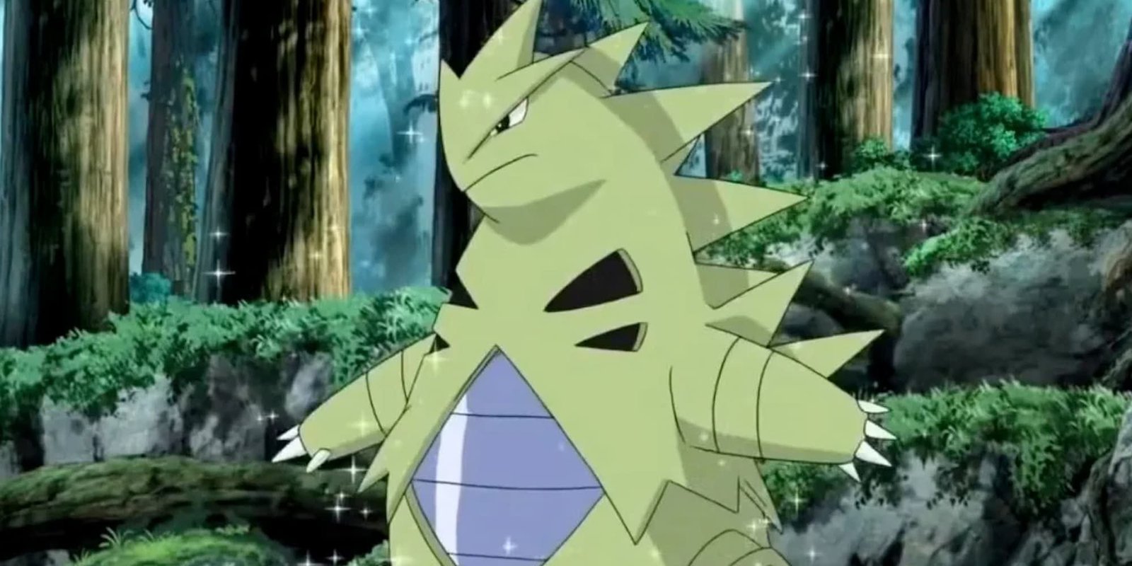 Tyranitar stands in a forest with a bit of a glimmer to it in the Pokemon anime.