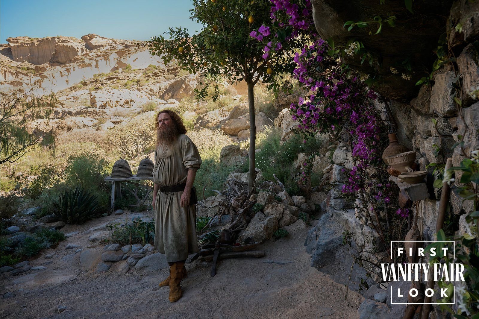 tom bombadil next to a wall of purple flowers in the rings of power