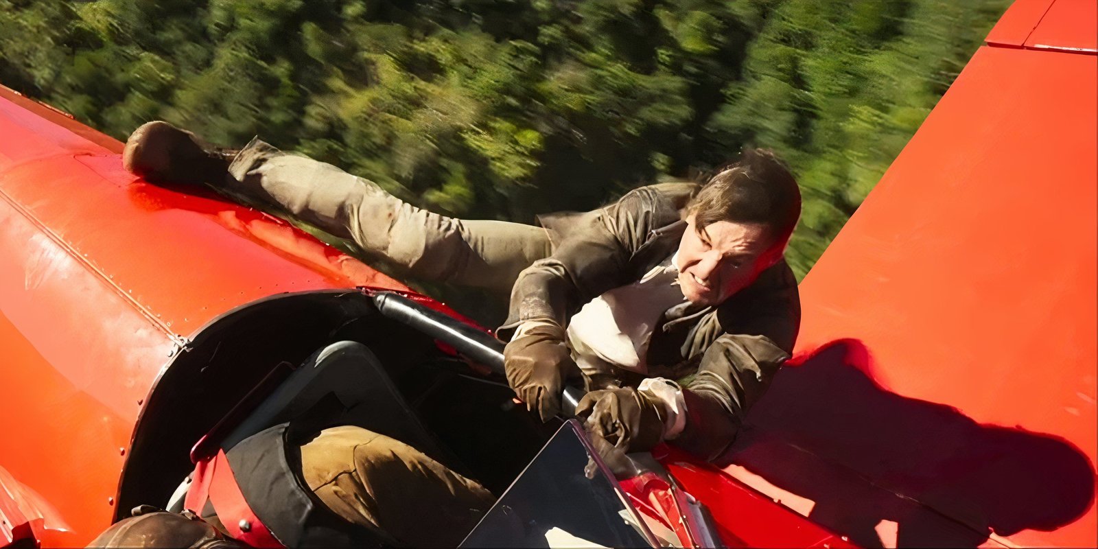 Tom Cruise hanging on for dear life on an enemy's red airplane in Mission Impossible Final Reckoning.