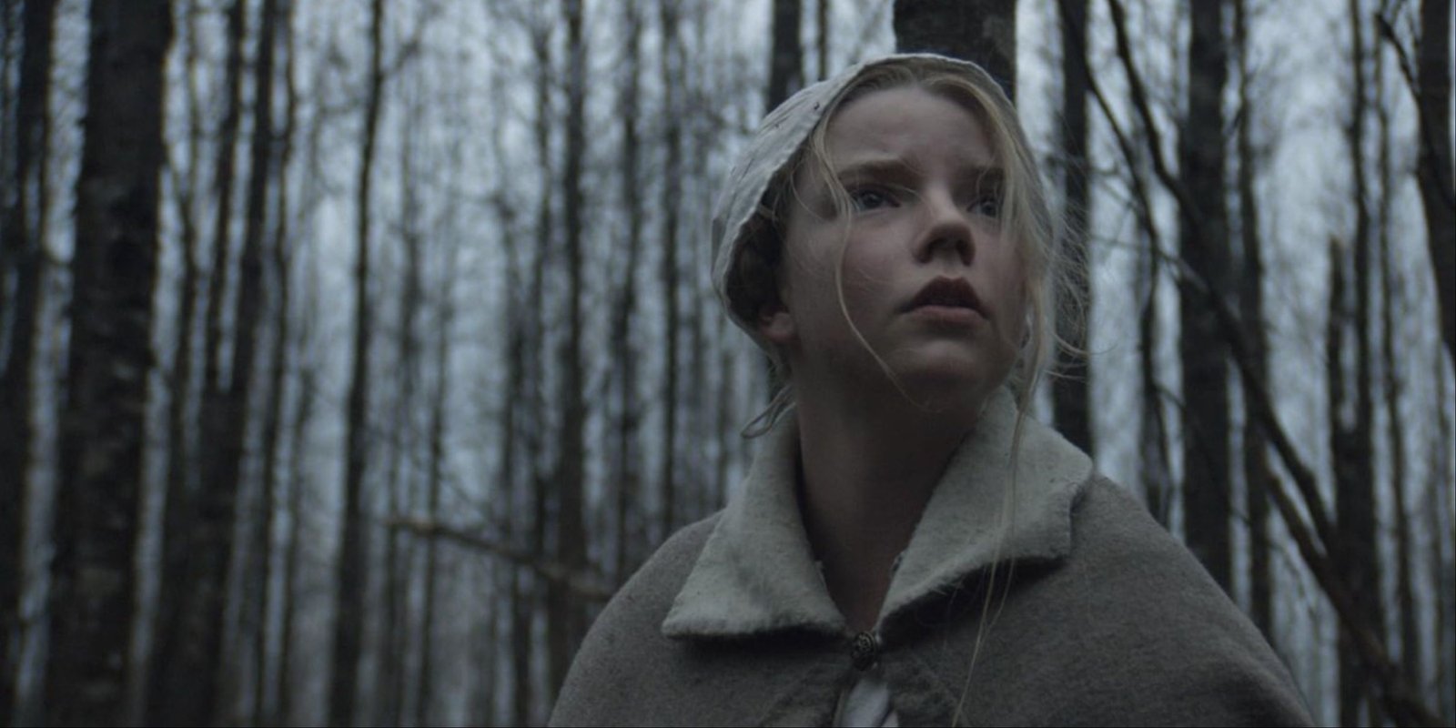 The Witch - A close-up of Anya Taylor-Joy's character, Thomasin, looking around frantically in the woods.