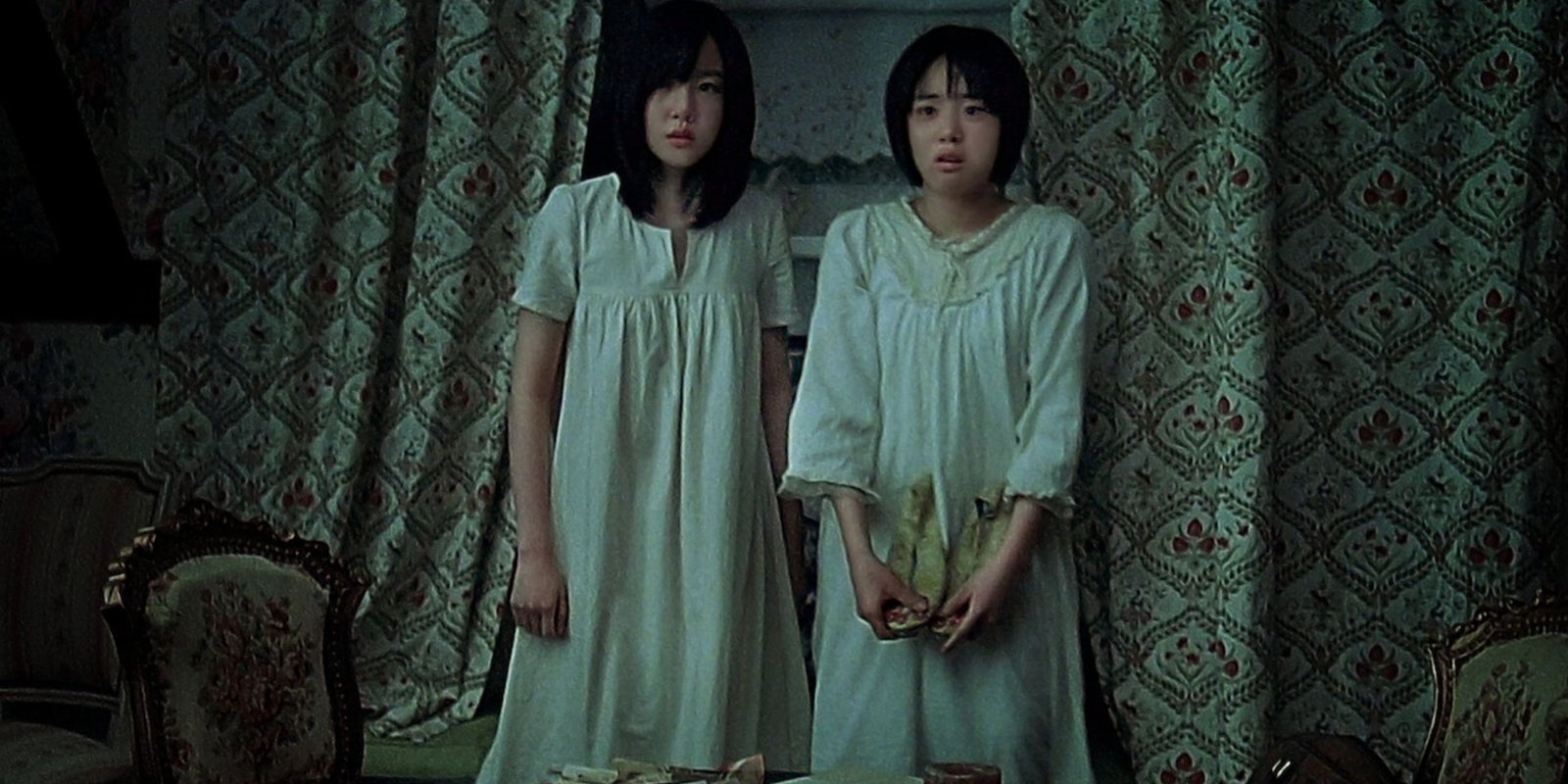 Su-mi and Su-yeon appear tense as they huddle against the window in A Tale Of Two Sisters.