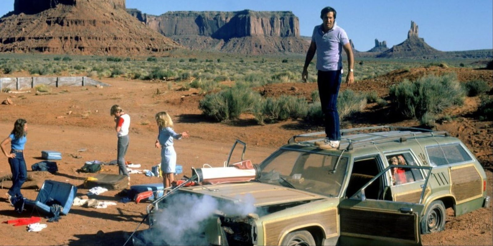 Chevy Chase standing on the hood of the busted-up family car as the Griswolds are trapped in the desert in Vacation.